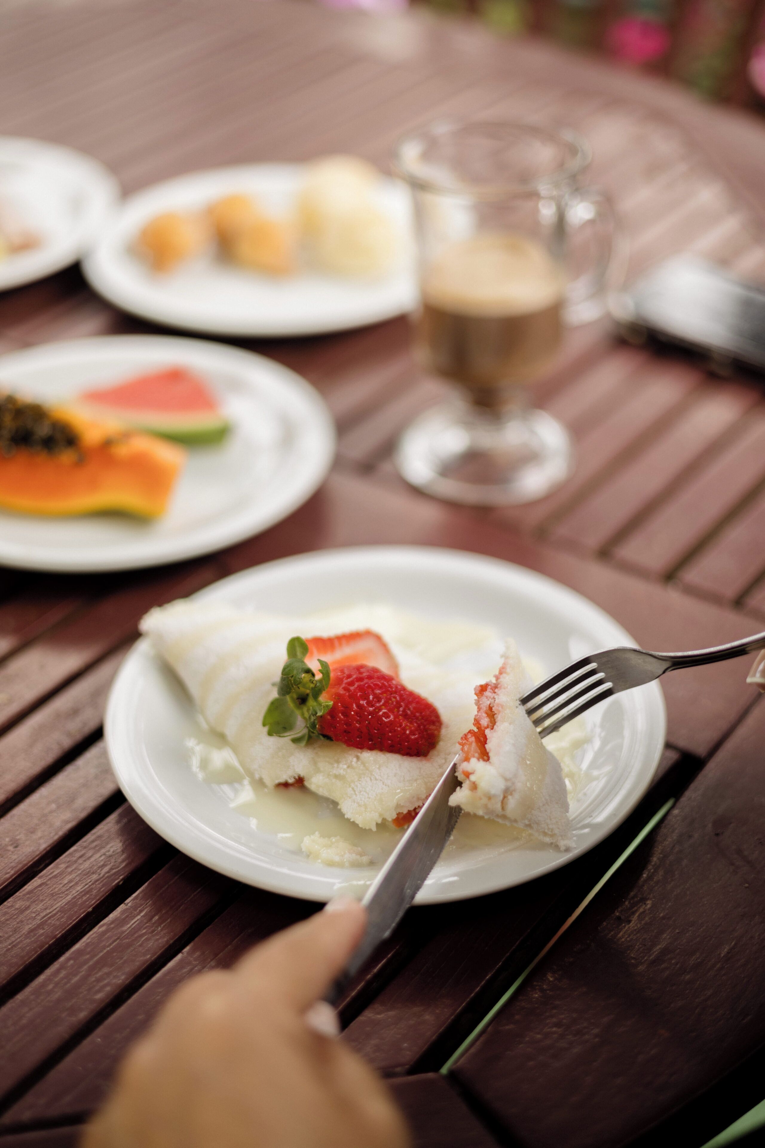 A dining table with plates of food and a glass of beverage.