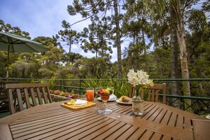 A wooden table with a fruit salad, a glass of juice, and a bottle of water. - Green Village Hotel (Camanducaia)