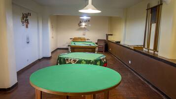 Une pièce comprenant une table de billard, une table de jeu de flipper et une chaise.