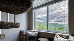 A room with a large window, a cushioned bench, and decorative pillows.