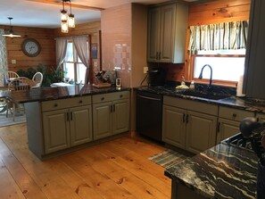 Una cocina con armarios de madera, encimera de mármol y comedor con mesa y sillas de madera.