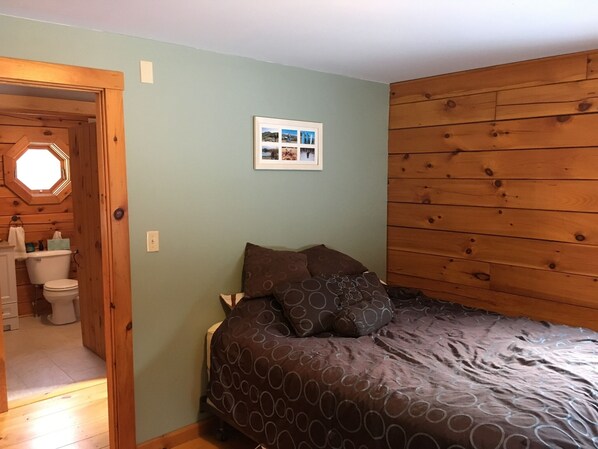 A bedroom with a wooden headboard, a bed with patterned bedding, and a framed photo on the wall.