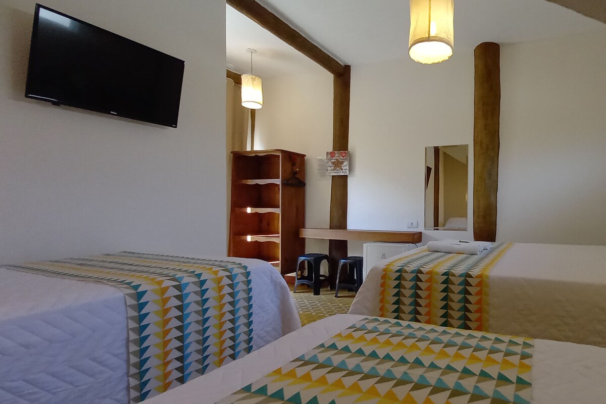 A hotel room with two beds, a TV, a desk, and a mirror.