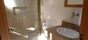 Un baño con cabina de ducha de vidrio, lavamanos blanco y retrete.
