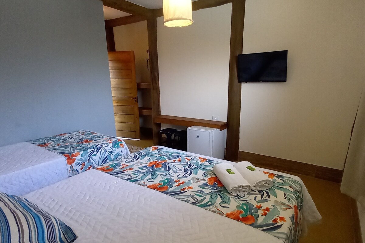 Habitación de hotel con dos camas, un televisor de pantalla plana y una escalera de madera.