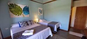 A hotel room with two beds, a nightstand, and a door. - Pousada Três Marias Ilhabela (Ilhabela)