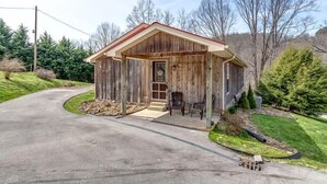 A rustic wooden building with a red roof, a front porch with two chairs, and a small window. - ATV Trail Access! Secluded Mountain Retreat (Duff)