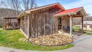 A rustic wooden building with a red roof, a porch with chairs, and a stone-tiled patio. - ATV Trail Access! Secluded Mountain Retreat (Duff)