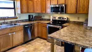 A kitchen with wooden cabinets, a stainless steel microwave, a stove, and a dishwasher.