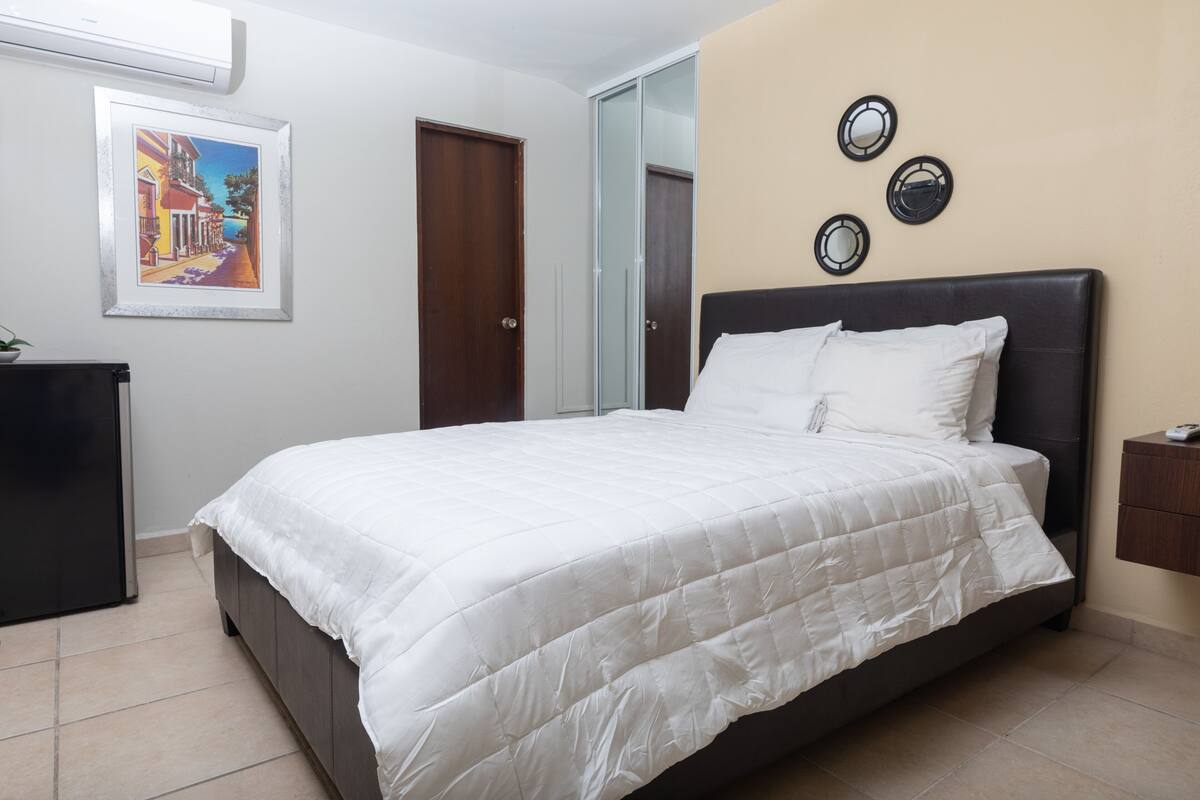 A bedroom with a large bed, a wardrobe, a mirror, and a framed picture on the wall.