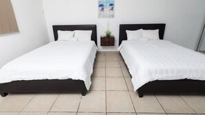 A hotel room with two single beds, a small nightstand with a vase, and a beach-themed wall art. - Red Sunset Beach Club (Cabo Rojo)