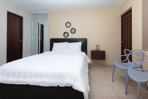 Un dormitorio con cama, mesita de noche, silla y armario.