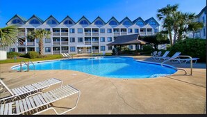 A hotel with a swimming pool, lounge chairs, and a covered pavilion. - Beachfront “Our Happy Place” Ground Level 2/2 sleeps 8 (Gulf Shores)