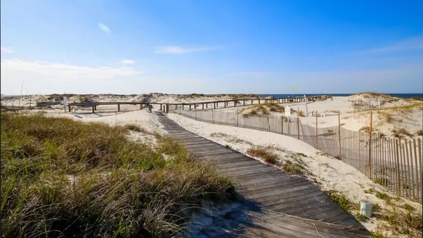 A wooden boardwalk leading to a beach area with a wooden fence and a small structure. - Beachfront “Our Happy Place” Ground Level 2/2 sleeps 8 (Gulf Shores)