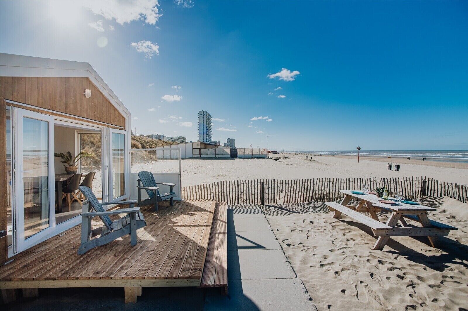 Una propiedad frente a la playa con terraza de madera, mobiliario exterior y vista a la playa y al océano.