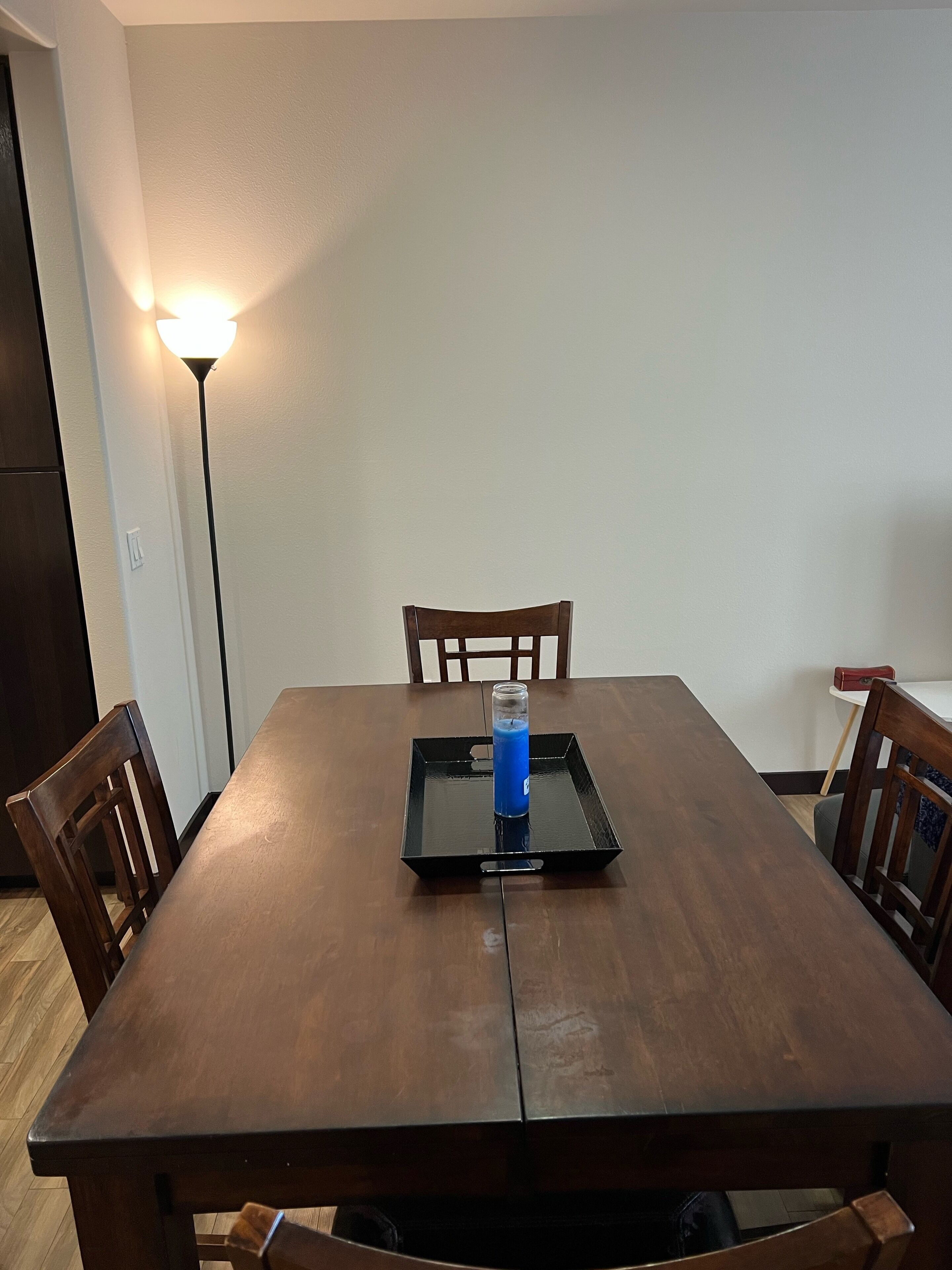 A dining table with chairs, a tray with a blue object, and a floor lamp.