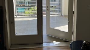 An open door leading to a balcony with a view of buildings and a swimming pool.