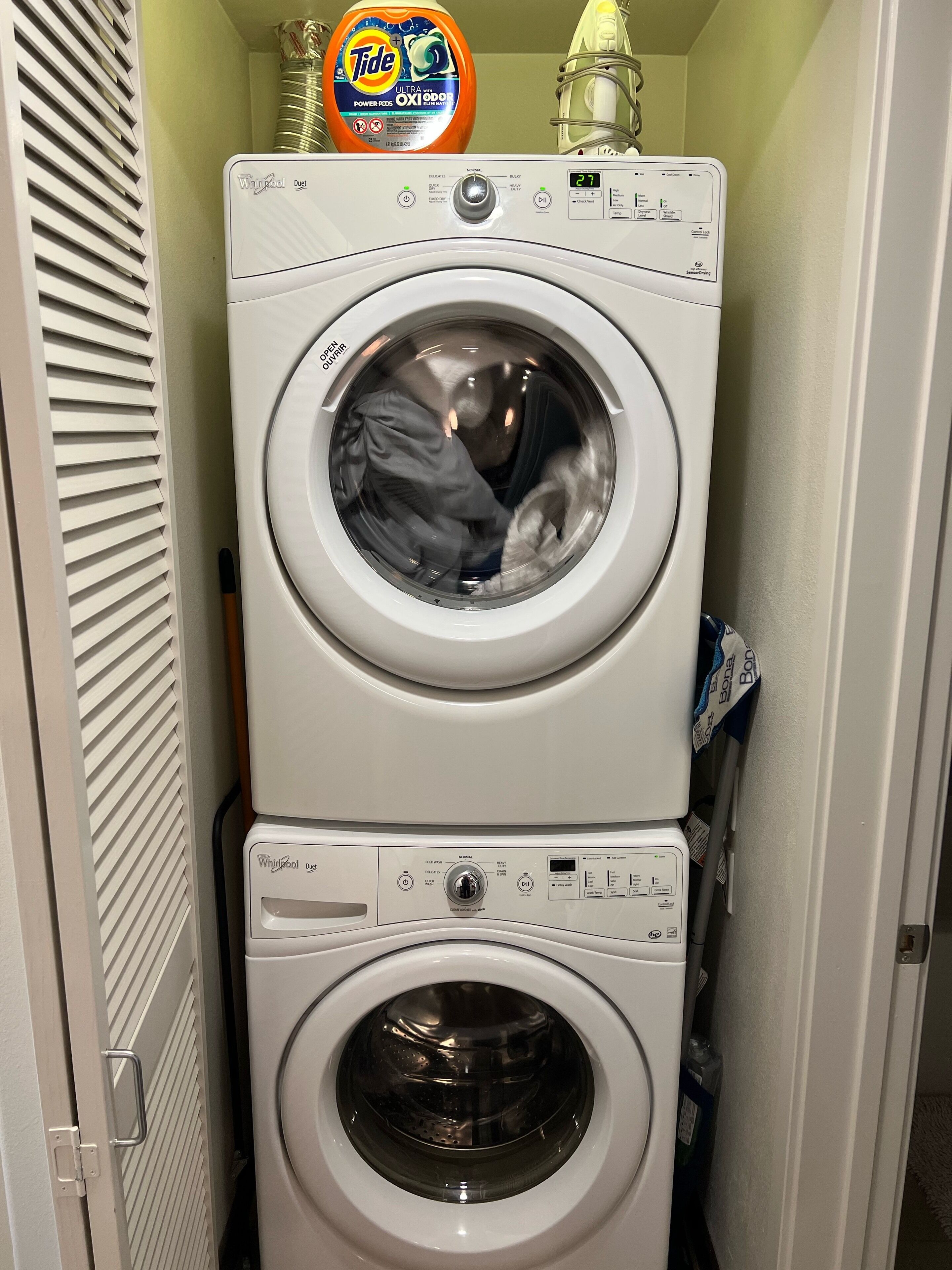 Una lavadora y secadora apiladas, con una caja de detergente Tide encima.