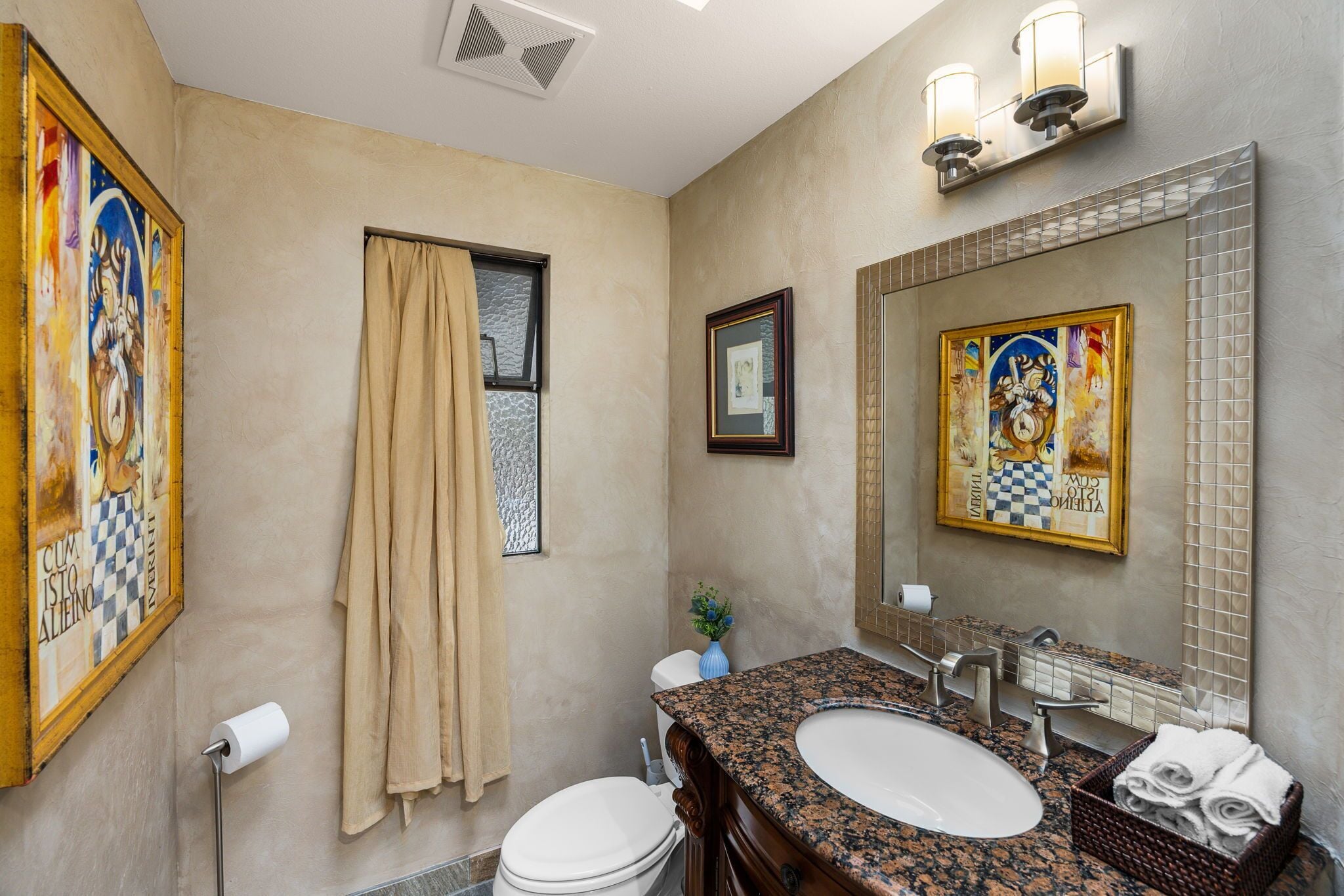 Een badkamer met een wastafel, toilet en een grote spiegel met een decoratieve lijst.