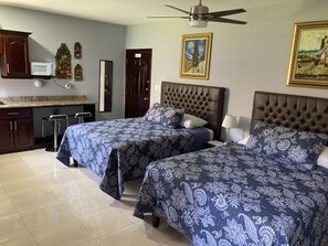 Un dormitorio con dos camas, una zona de cocina y una mesa de comedor.