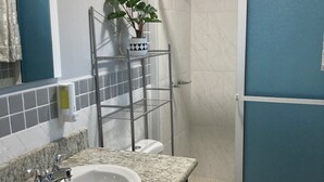 Une salle de bain avec un lavabo blanc, une douche et une porte bleue.
