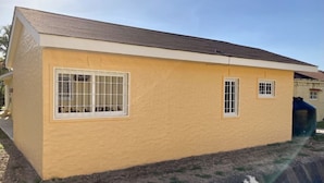 Il s’agit d’un bâtiment d’un seul étage, à la façade jaune et au toit brun. Il possède une grande fenêtre avec des barreaux blancs et deux fenêtres plus petites, sans barreaux.