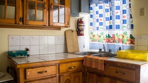 Una cocina con armarios de madera, un lavamanos y una ventana con una cortina colorida.