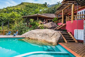 A pool with wooden steps and a red building in the background. - Mansão Sobreomar - Ilhabela (Ilhabela)
