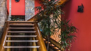 A wooden staircase with a red wall and stone accents. - Mansão Sobreomar - Ilhabela (Ilhabela)