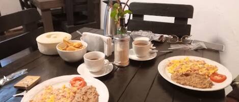 A dining table with plates of food, cups, and a pitcher.