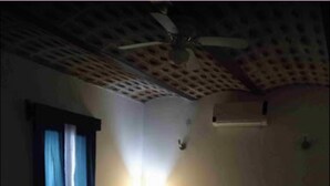 A dimly lit room with a bed, a small table, and a ceiling fan. - ANTIQUE Garcia (Garcia)