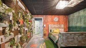 A bedroom with a bed, a wall clock, and a floral wall decoration. - HOCHATOWN Charming Hotel Garden suite. (Broken Bow)