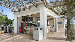An outdoor café with a wooden pergola, a menu board, and seating arrangements.