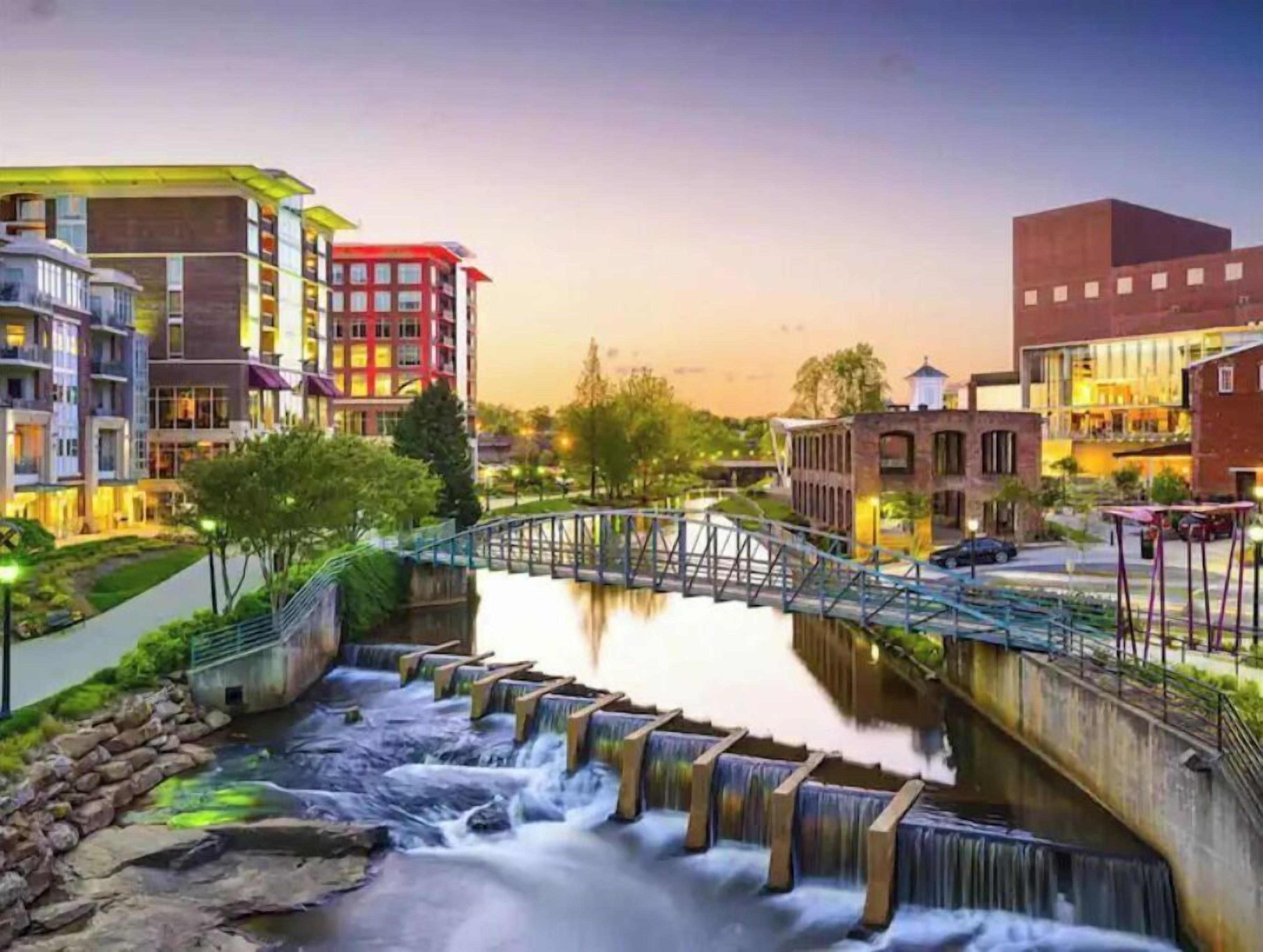 Una zona urbana moderna con un río, un puente y edificios con balcones.