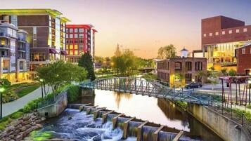Una zona urbana moderna con un río, un puente y edificios con balcones.