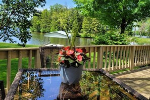 A wooden deck with a glass table and a flower pot.