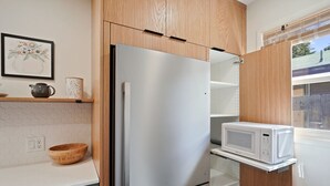 Una cocina con un refrigerador de acero inoxidable, un microondas y un tazón de madera en la encimera.