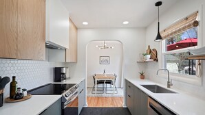 Una cocina moderna con una isla central, electrodomésticos integrados y vistas a un comedor a través de un arco.