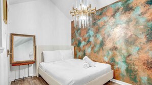 Une chambre moderne avec un grand lit, un miroir et un mur à texture.