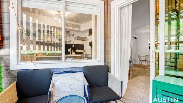 Une cuisine moderne avec des meubles blancs et une grande fenêtre. On y trouve un coin repas avec une table et deux chaises.