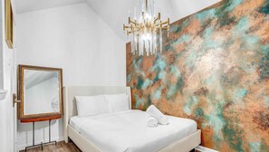 A modern bedroom with a large bed, a mirror, and a textured wall.