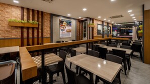 Un restaurante con paredes de ladrillo, mesas de madera y sillas negras.