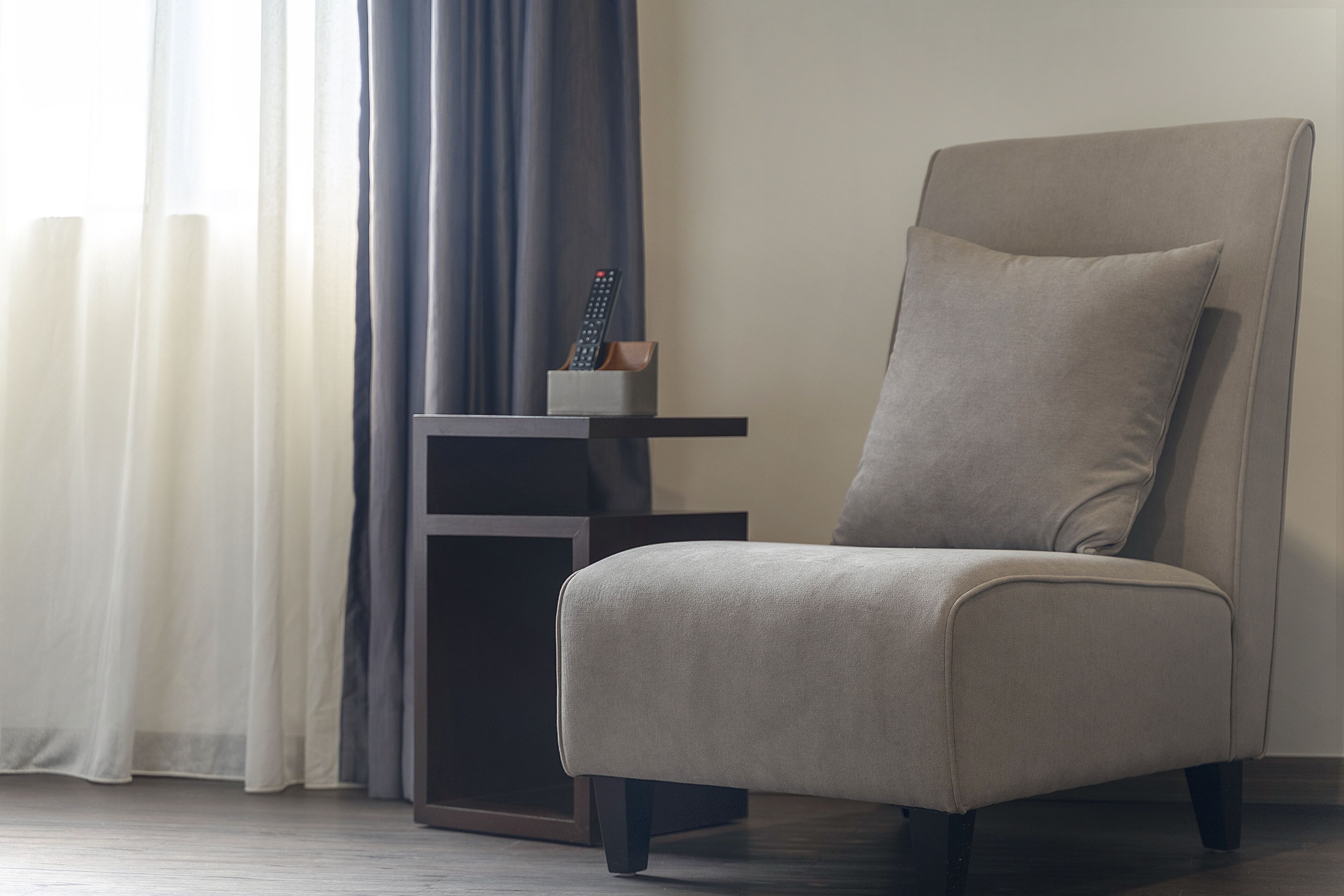 A modern living room with a large armchair, a side table, and a remote control on the table.