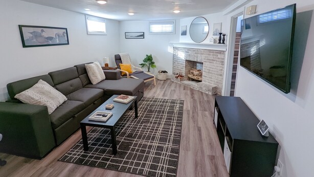 Uma sala de estar moderna com um sofá modular, lareira, televisão grande e tapete estampado.