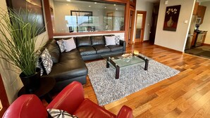 A modern living room with a sectional sofa, a glass coffee table, and a red chair.