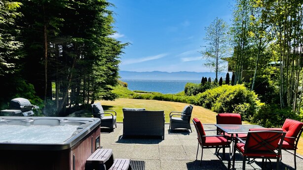 A patio area with a hot tub, outdoor furniture, and a view of the ocean.