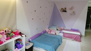 Une chambre d’enfant avec un lit, des étagères remplies de jouets et un mur décoré d’étoiles.