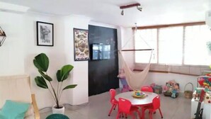 Un salon avec un canapé, une table à manger et des chaises, un fauteuil suspendu et une guitare.