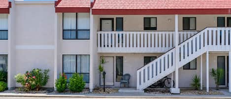 Un motel de dos pisos con techo rojo, un balcón en el segundo piso y un estacionamiento que indica 'GUEST 128'.