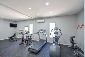 A gym with treadmills, stationary bikes, and a bench.